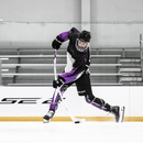 Junior hockey player skating and shooting with Bauer Pulse 2 white ice hockey stick on rink