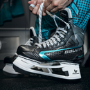 Bauer Supreme Fuse ice hockey skate being laced up in a locker room setting