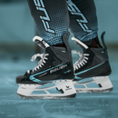 Bauer Supreme Fuse ice hockey skates on ice, showing black and teal colorway with white blade holder